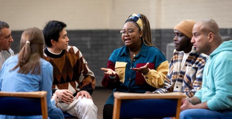 A support worker leading a group discussion with people seated in a circle
